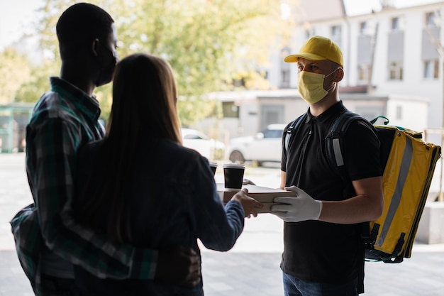 Cacasian man in face mask works on the delivery of pizza