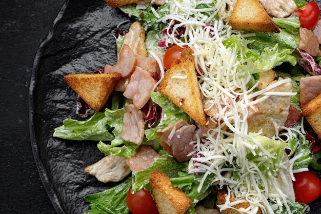 Caesar salad on a black plate Close up