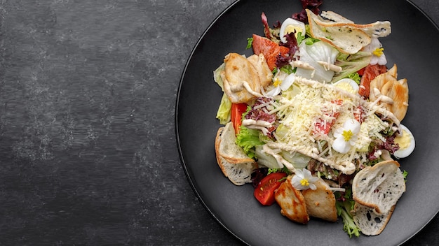 Caesar salad with chicken on a black plate