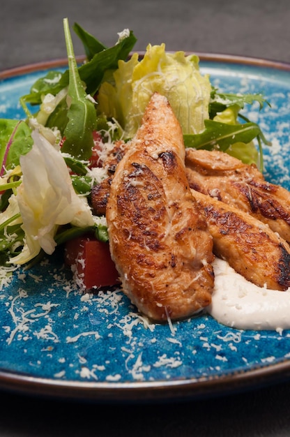 Caesar salad with chicken fillet on a blue plate Closeup