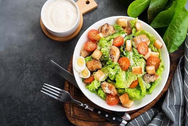 Caesar salad with chicken fillet, cherry tomatoes and croutons, traditional Italian food, top view, copy space