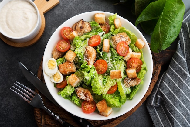 Caesar salad with chicken fillet, cherry tomatoes and croutons, traditional Italian food, top view