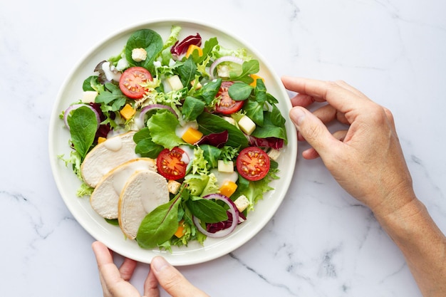 Caesar salad with chicken lettuce tomato cheese and sauce on white background