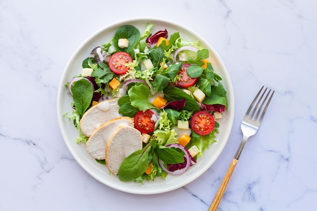 Caesar salad with chicken lettuce tomato cheese and sauce on white background