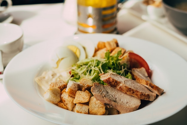 Caesar salad with chicken on the white plate