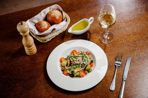 Caesar salad with croutons, quail eggs, cherry tomatoes and grilled chicken in wooden table