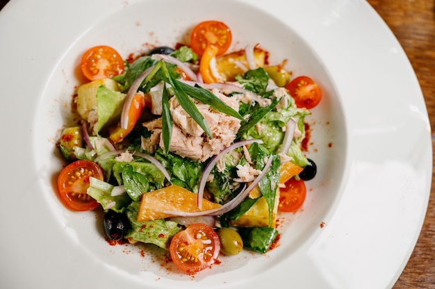 Caesar salad with croutons, quail eggs, cherry tomatoes and grilled chicken in wooden table