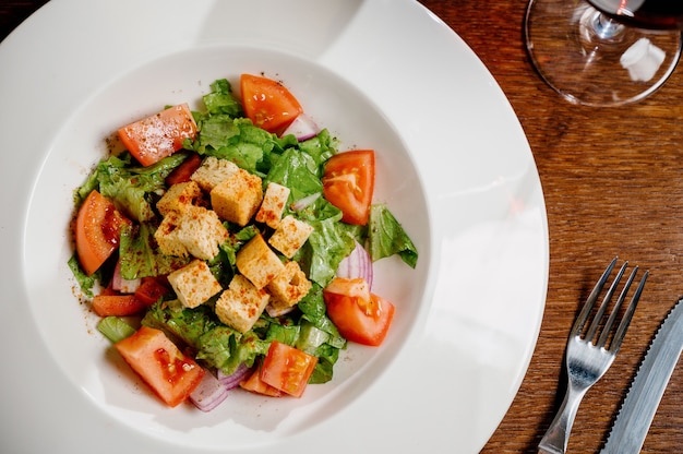 Caesar salad with croutons, quail eggs, cherry tomatoes and grilled chicken in wooden table