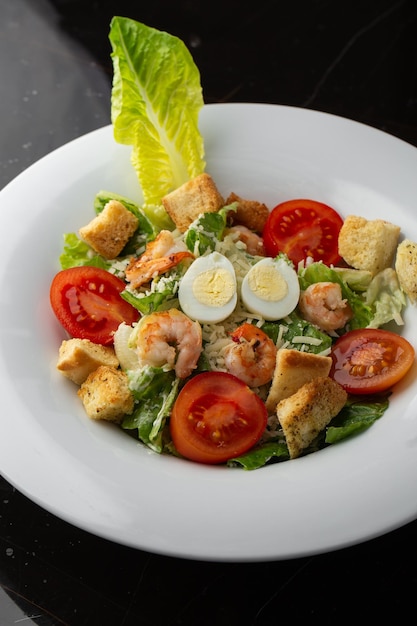 Caesar salad with grilled shrimps tomato boiled egg lettuce croutons and green sauce Top view closeup on brown round plate with fresh vegetable