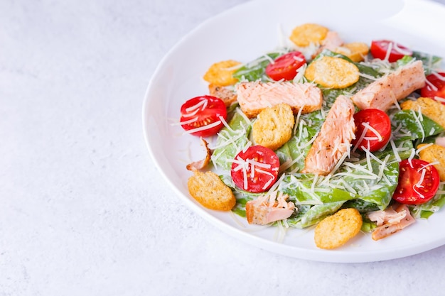 Caesar salad with red fish salmon trout cherry tomatoes croutons parmesan cheese and romaine Traditional American dish Copy space Closeup selective focus