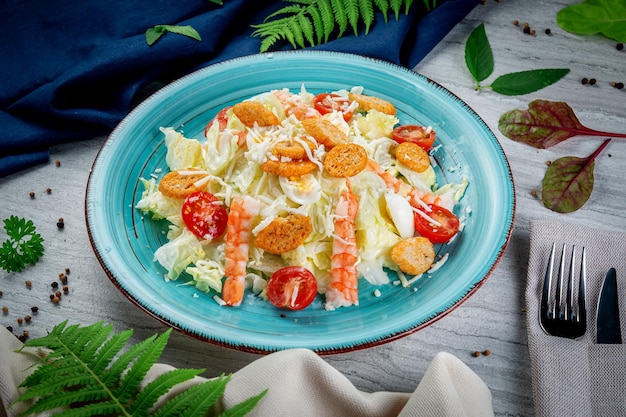 Caesar salad with shrimp in a plate on a light table