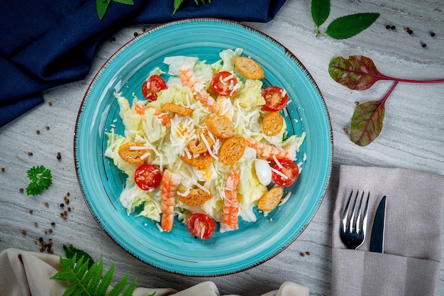 Caesar salad with shrimp in a plate on a light table