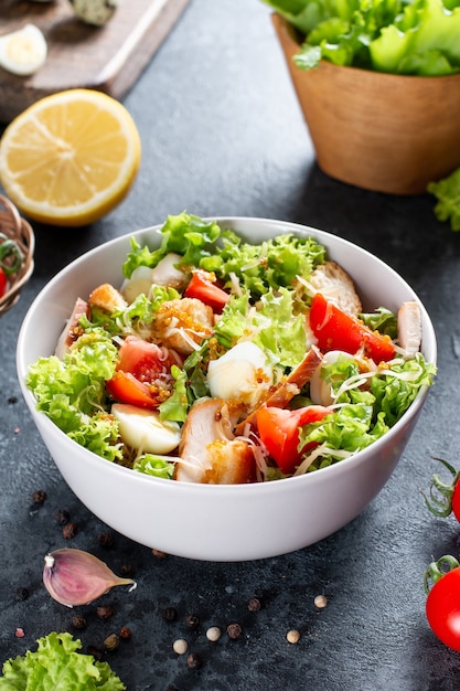 Caesar Salad with smoked chicken and parmesan on a plate on dark background. Top view