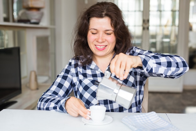 Cafe drinks and meal concept  young woman with coffee pot pouring coffee in cup