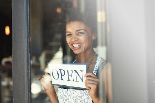 Cafe open sign window portrait and happy woman with smile for retail service restaurant welcome or coffee shop opening Small business owner board and person smiling for entrepreneur startup store