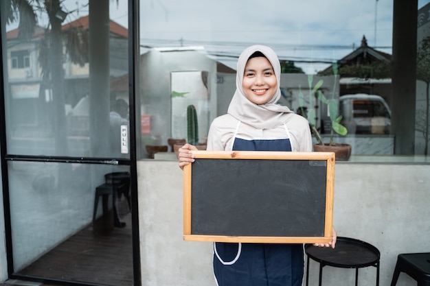 Cafe veiled waitress standing holding a blackboard