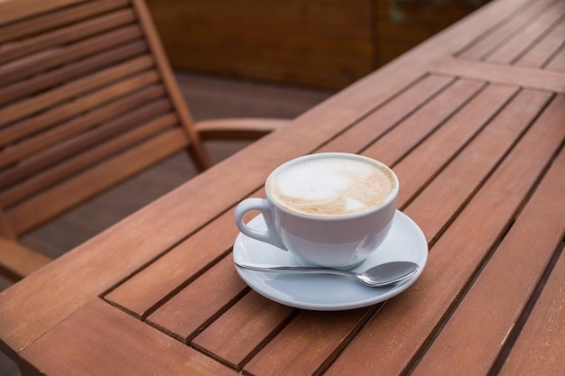 Caffe Latte Cup of coffee with a sweet cookie Good morning drink Rustic wooden background Close upBreakfast coffee Cappuccino art on vintage wooden table