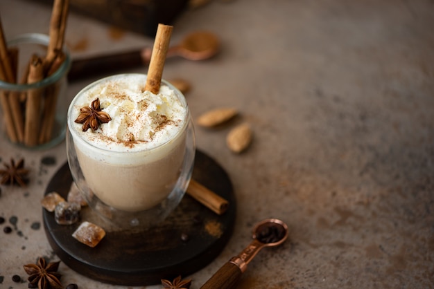 Caffe latte with whipped cream, cinnamon and anise in a glass