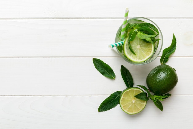 Caipirinha Mojito cocktail vodka or soda drink with lime mint and straw on table background Refreshing beverage with mint and lime in glass top view flat lay