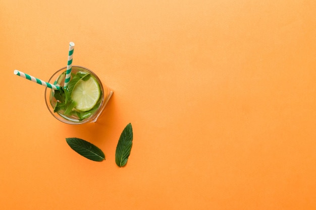 Caipirinha Mojito cocktail vodka or soda drink with lime mint and straw on table background Refreshing beverage with mint and lime in glass top view flat lay