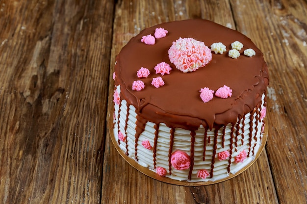 Cake covered with chocolate with pink roses on the old board