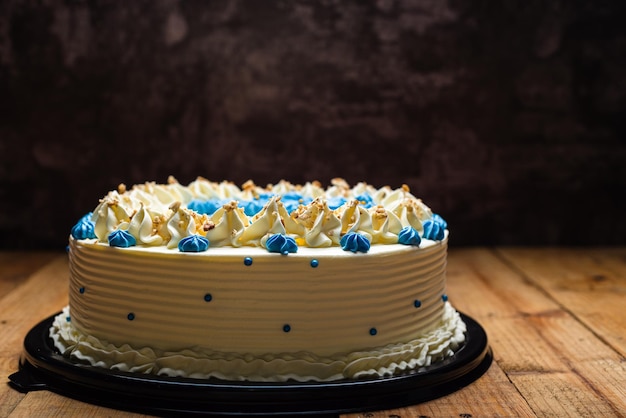 Cake decorated with blue cream cheese flowers and cracked walnut Cake on wooden table