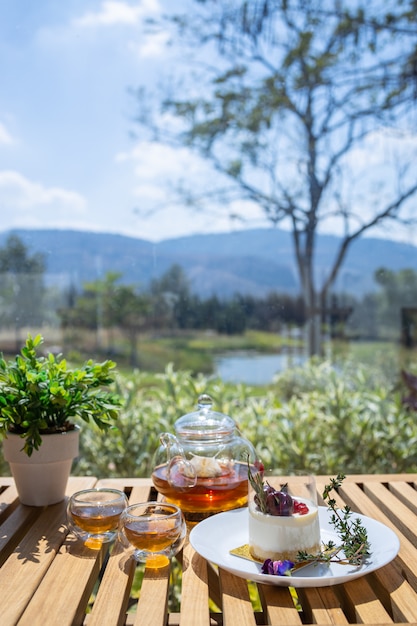 Cake and hot tea served on the table with natural views for relaxing moments.