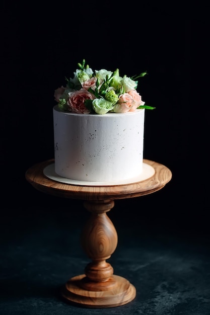 Cake is decorated with flowers on a dark background.