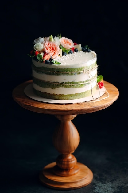 Cake is decorated with flowers on a dark background.