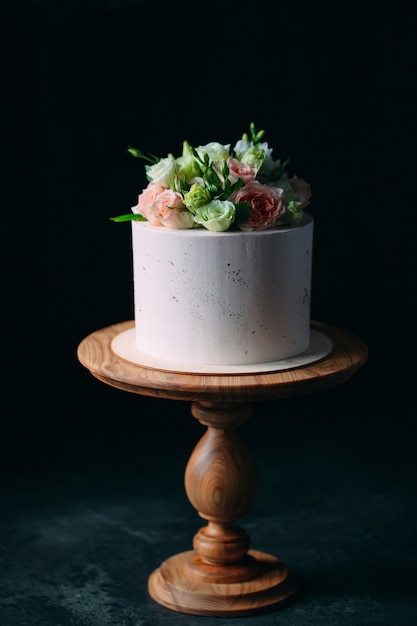 Cake is decorated with flowers on a dark .