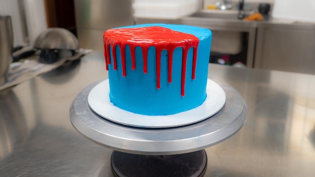 Cake pastry chef designer decoration a blue frosted icing cake for further decoration with red dripping with ganache