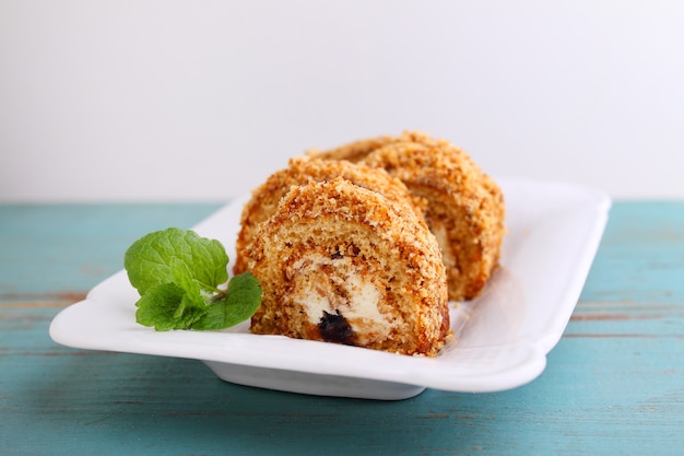 Cake rolls with butter cream decorated with mint on a plate on a light background selective focus