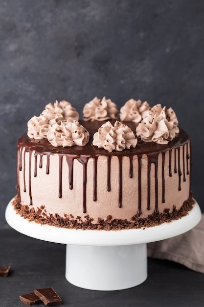 Cake with coffee cheese cream and chocolate topping on a white cake stand