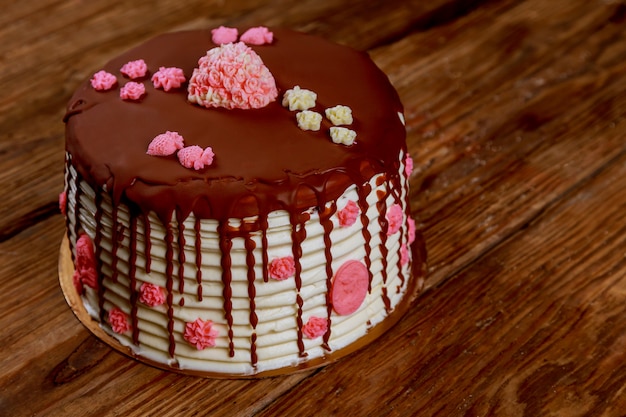 Cake with cream and chocolate with roses on the old board