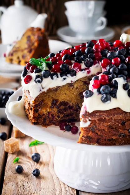 Cake with fresh berries and cream on old wooden surface. Selective focus.