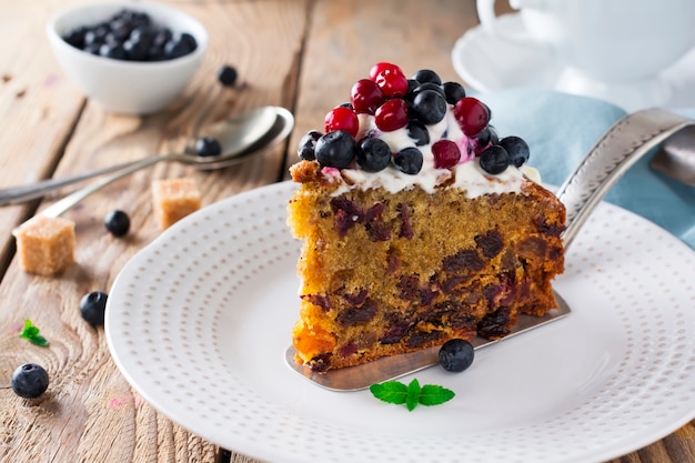 Cake with fresh berries and cream on old wooden surface. Selective focus.