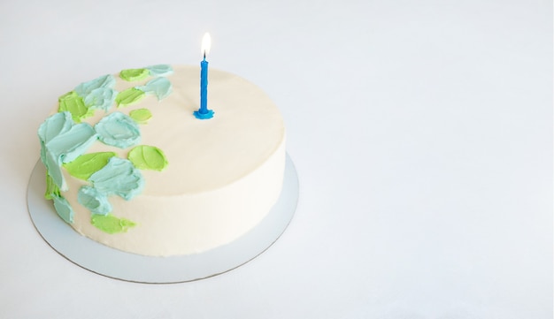 Cake with green and blue abstract decor and one candle. copy space.