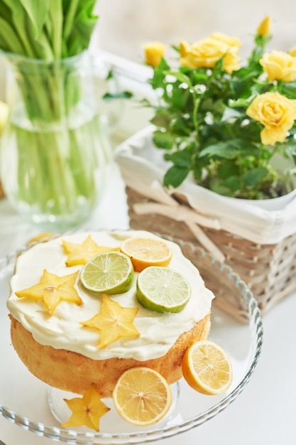 cake with lemons, limes, carambola on the table next to the tulips