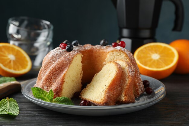 Cake with powdered sugar, berries and mint on wooden background