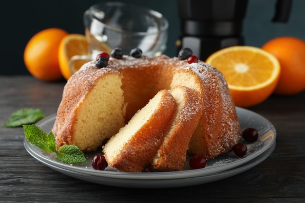 Cake with powdered sugar, berries and mint on wooden background