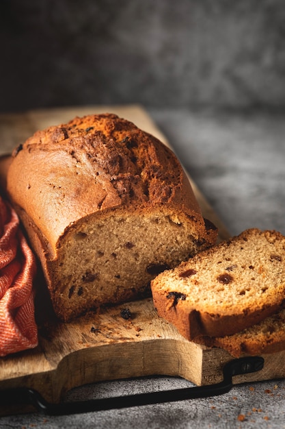 Cake with raisins on a wooden board, homemade baked goods with dried fruits, copy space, gray background