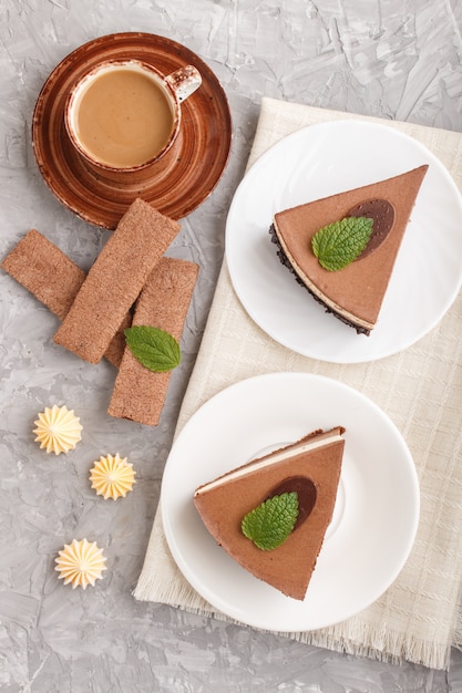 Cake with souffle milk chocolate cream with cup of coffee on a gray concrete surface. top view, close up.