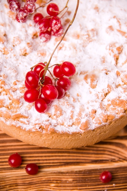 Cake on a wooden table decorated with icing sugar and red berries