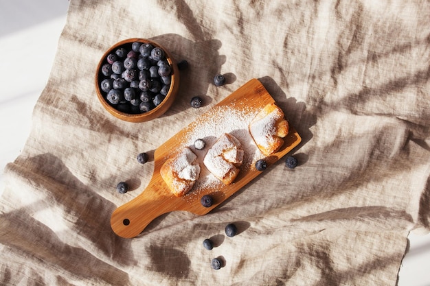 Cakes with blueberries sprinkled with icing sugar on a wooden background Top view Healthy eating Breakfast idea for children and adults