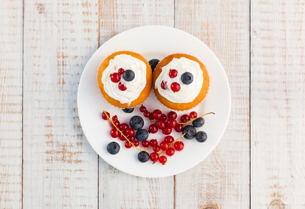 Cakes with cream and berries on wooden boards