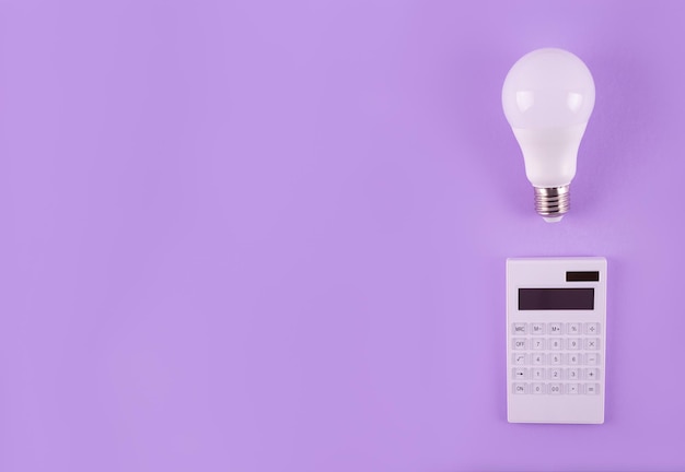 Calculation of electricity costs Calculator and energysaving light bulb on a purple background