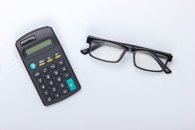 Calculator and classic eyeglasses on a white.