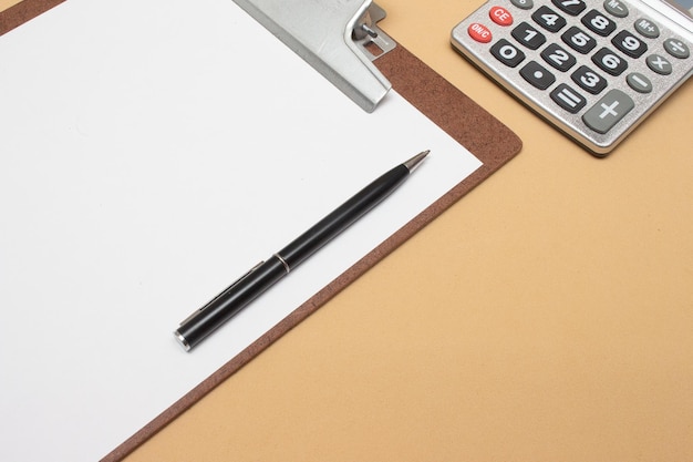 Calculator and clipboard on office table