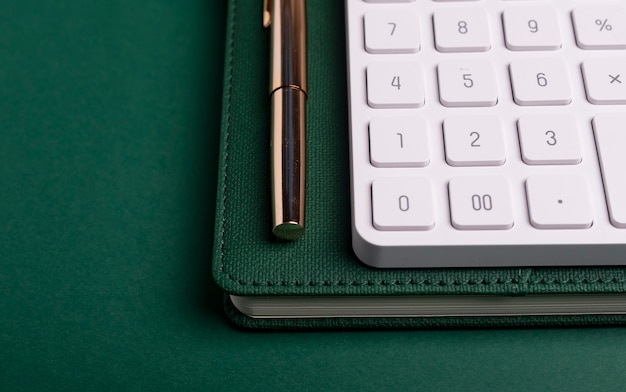 Calculator on green table and notebook with pen. Workplace of accountant.