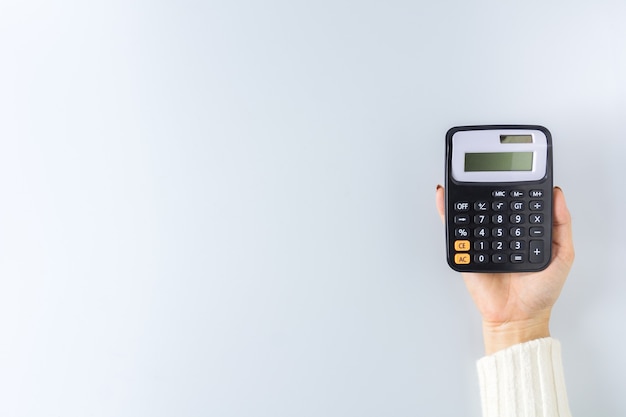 A calculator in a hand on white wall. - Saving money for finance accounting concept.